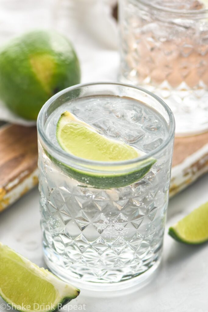 glass of vodka tonic with ice and lime wedge