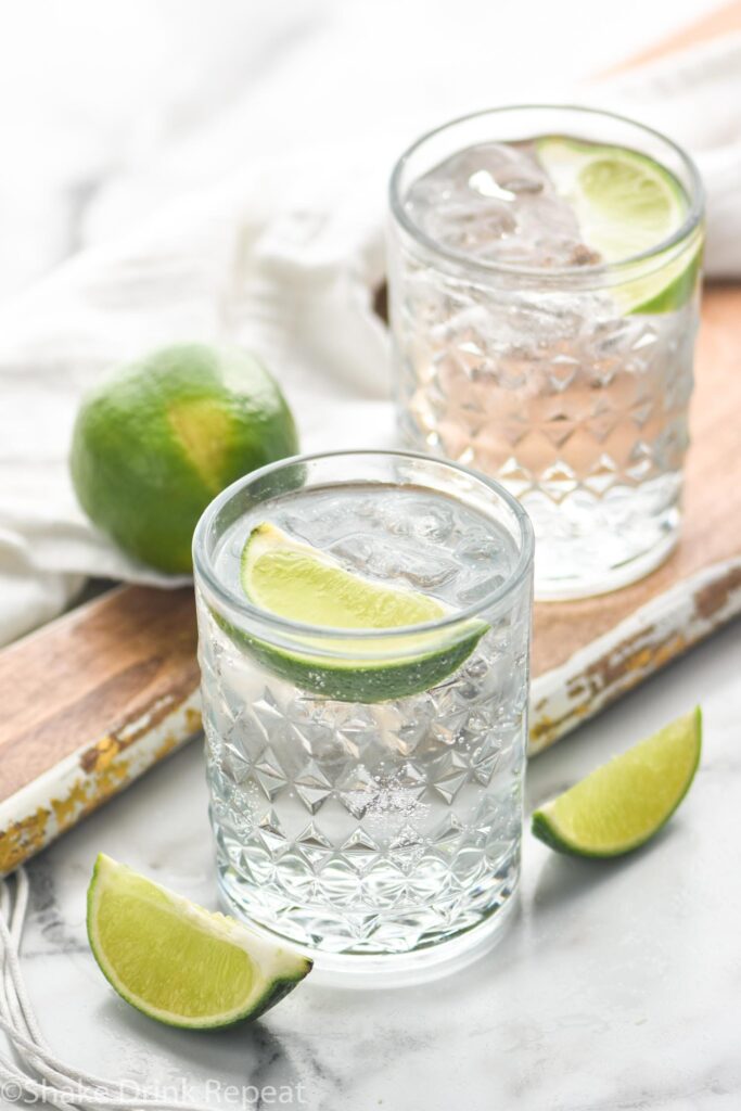 two glasses vodka tonic with ice and lime wedge