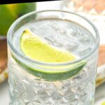 glass of vodka tonic cocktail with ice and lime wedge