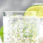 glass of vodka tonic with ice and lime wedge