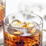 Glass of Black Russian with ice, surrounded by coffee beans