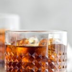 Glass of Black Russian with ice, surrounded by coffee beans