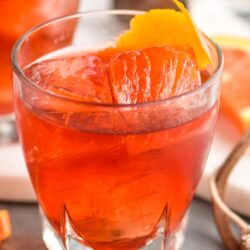 glass of boulevardier cocktail with ice and orange garnish