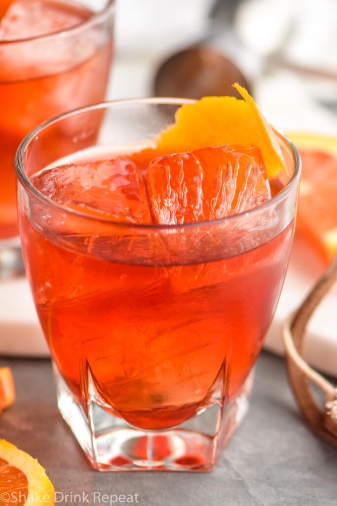 glass of boulevardier cocktail with ice and orange garnish