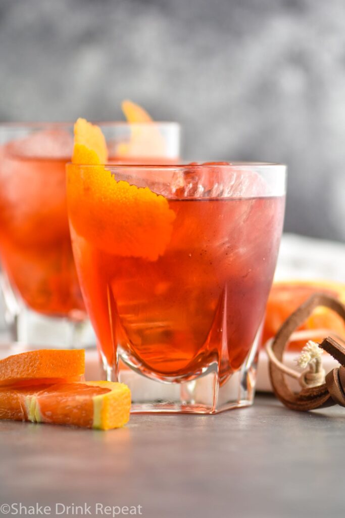 two glasses of boulevardier with ice and orange garnish