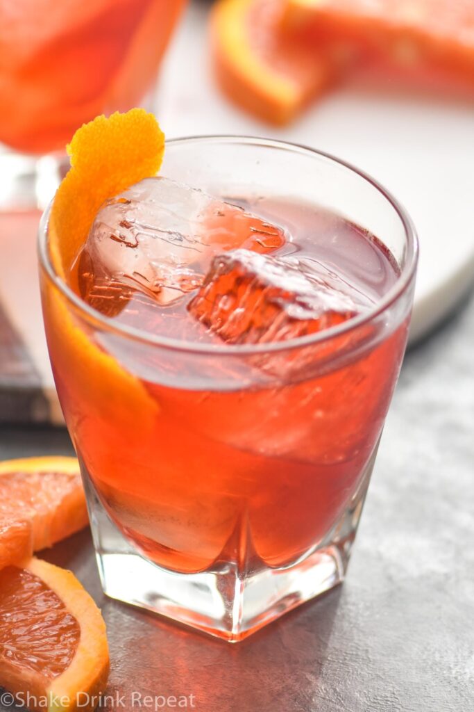 glass of boulevardier cocktail with ice and orange garnish