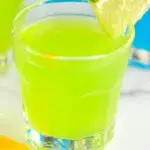 shot glass with green and blue kamikaze shot with orange and lime wedge