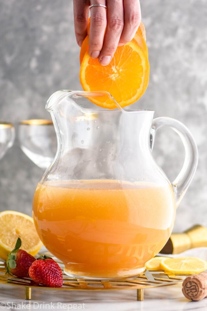 pitcher of mimosa sangria recipe with orange slices and strawberry