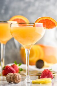 two glasses mimosa sangria with orange slices and strawberries