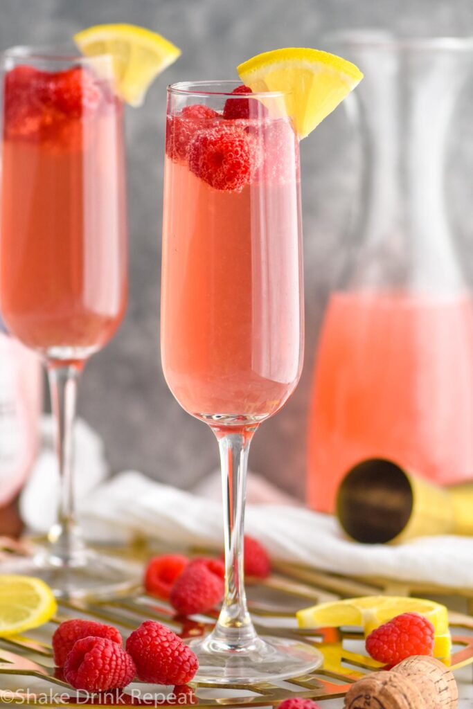 two glasses pink mimosa recipe with lemonade and raspberries