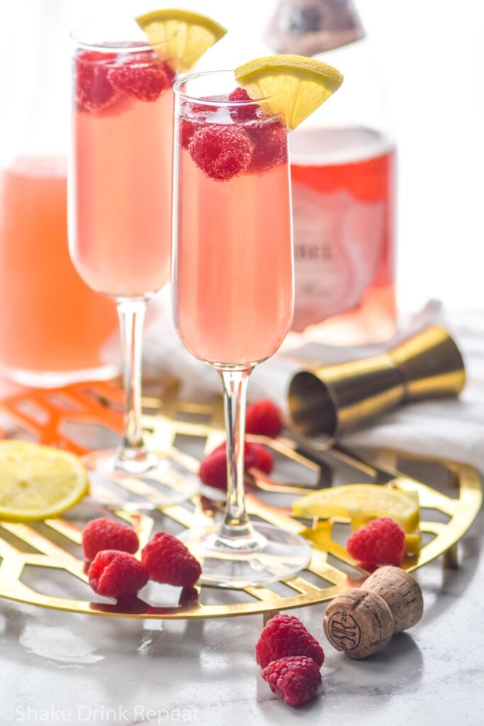 two glasses of pink mimosa with rosé, sliced lemon and raspberries