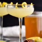 glass of bees knees cocktail with lemon twist and honey syrup