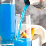 two glasses of blue kamikaze recipe with orange and cherry garnish