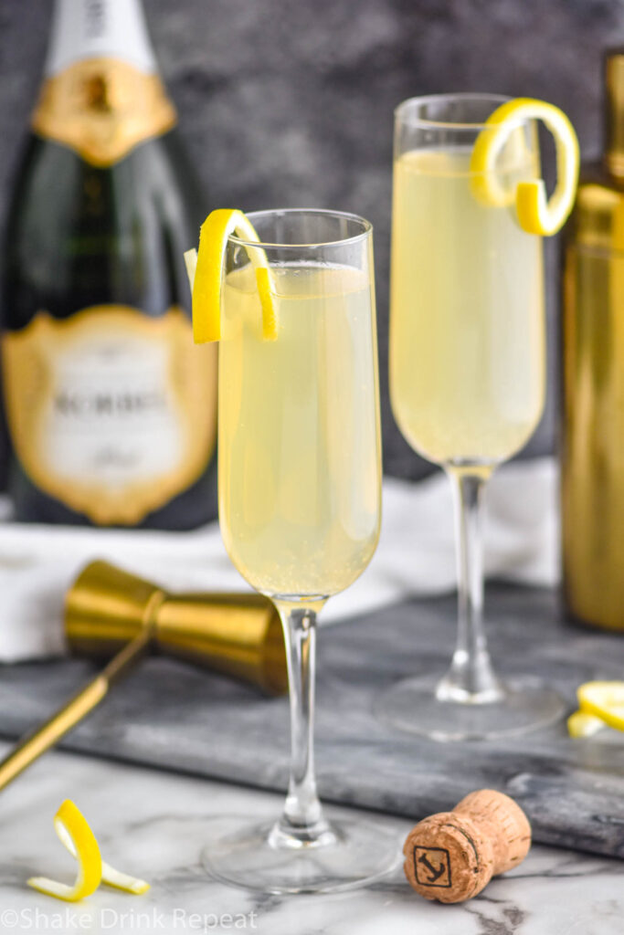 two glasses of french 75 with lemon twist, shaker, and champagne