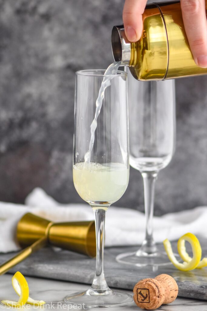 making a french 75 cocktail with shaker, glass and lemon twist