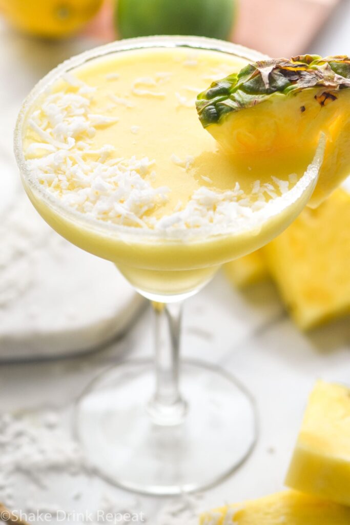 sugared rim glass of pineapple malibu margarita with pineapple garnish and coconut