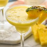 two sugared rim glasses of malibu pineapple margarita with coconut garnish