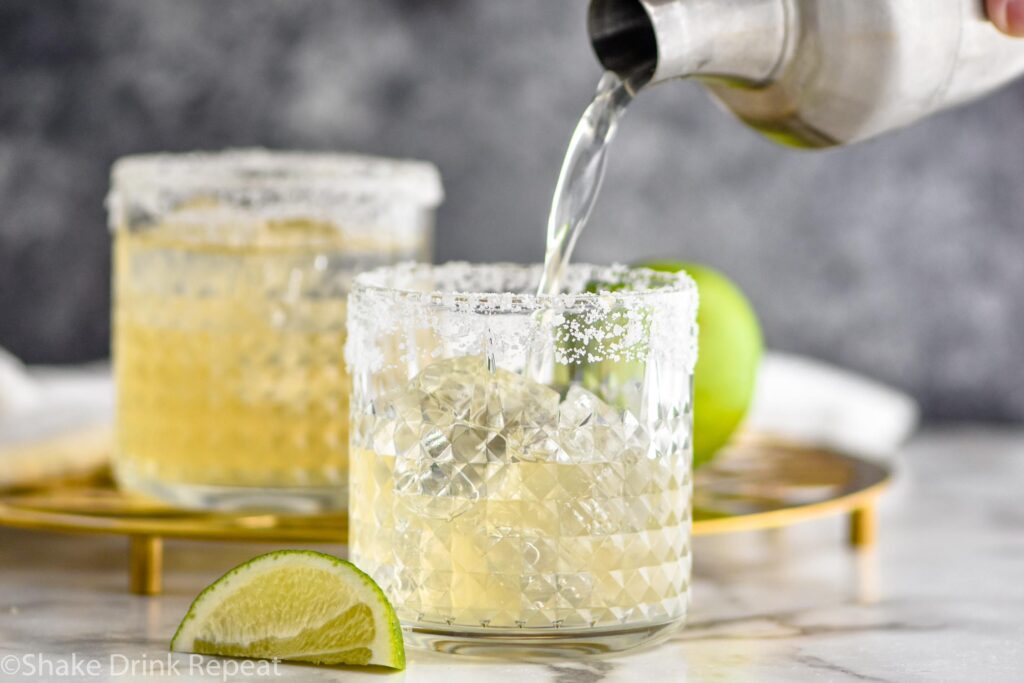 two glasses of margarita with salted rim, ice and lime