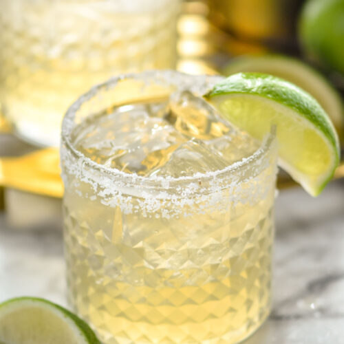 two glasses of margarita with ice, salted rim and lime