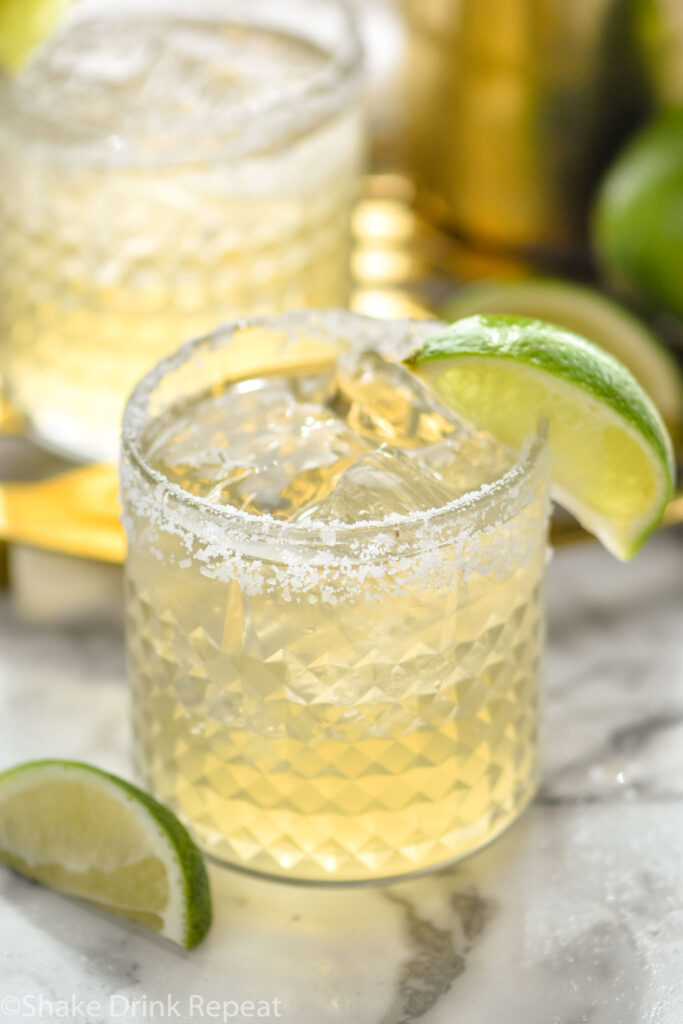 two glasses of margarita with ice, salted rim and lime