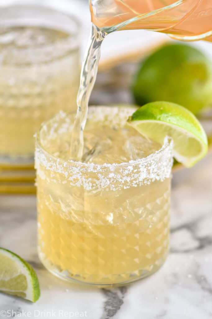 glass of margarita with ice, salted rim, and lime