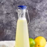 bottle of homemade margarita mix with lemons and limes