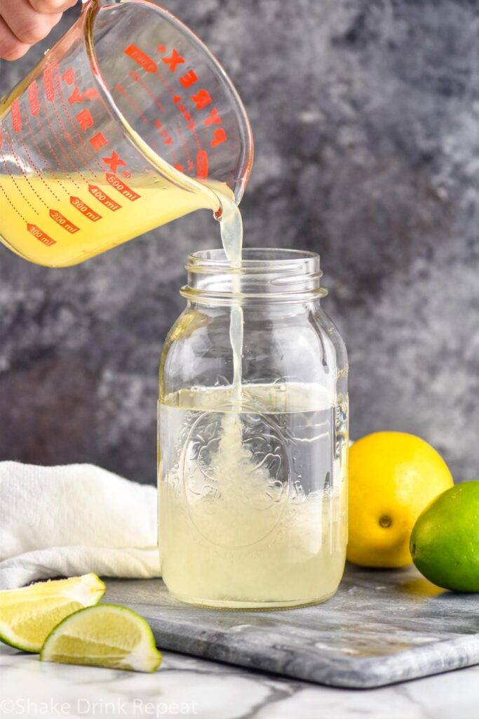making homemade margarita mix recipe in a jar with lemons and limes