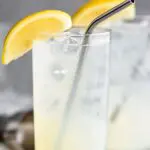 two glasses of rum collins with ice, lemon and straws