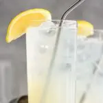 two glasses of rum collins with ice, lemon and straws