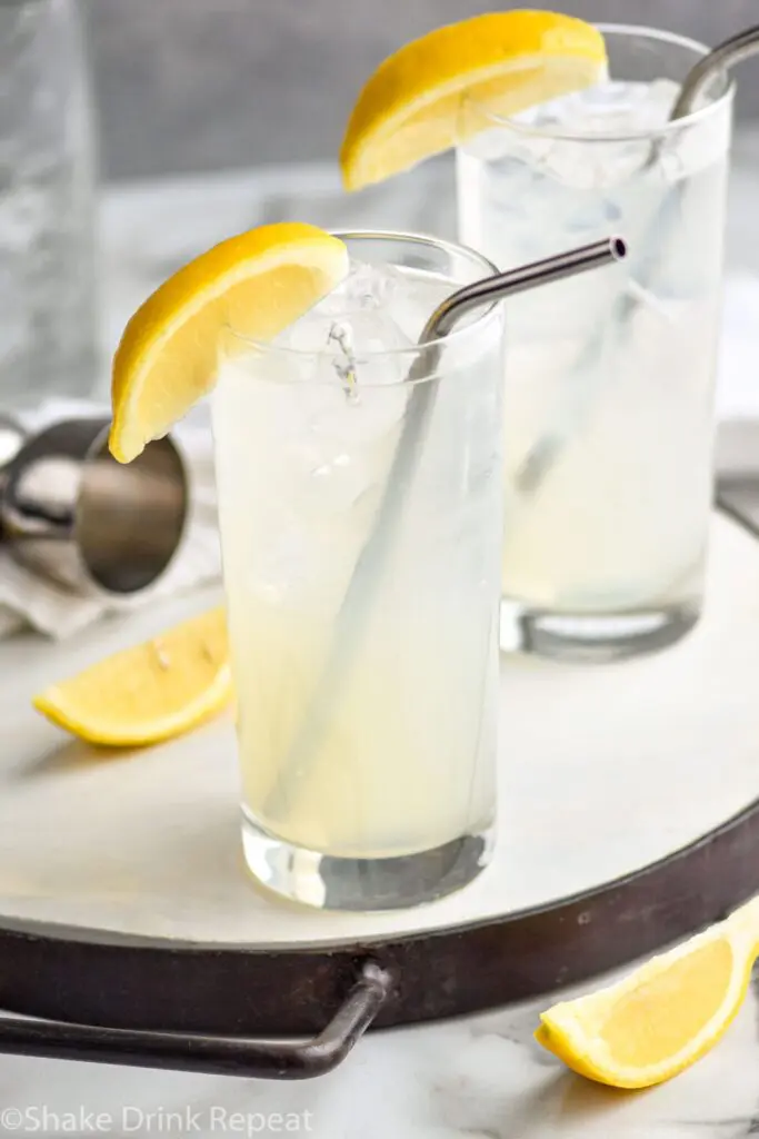 two glasses of rum collins with ice, lemon and straws