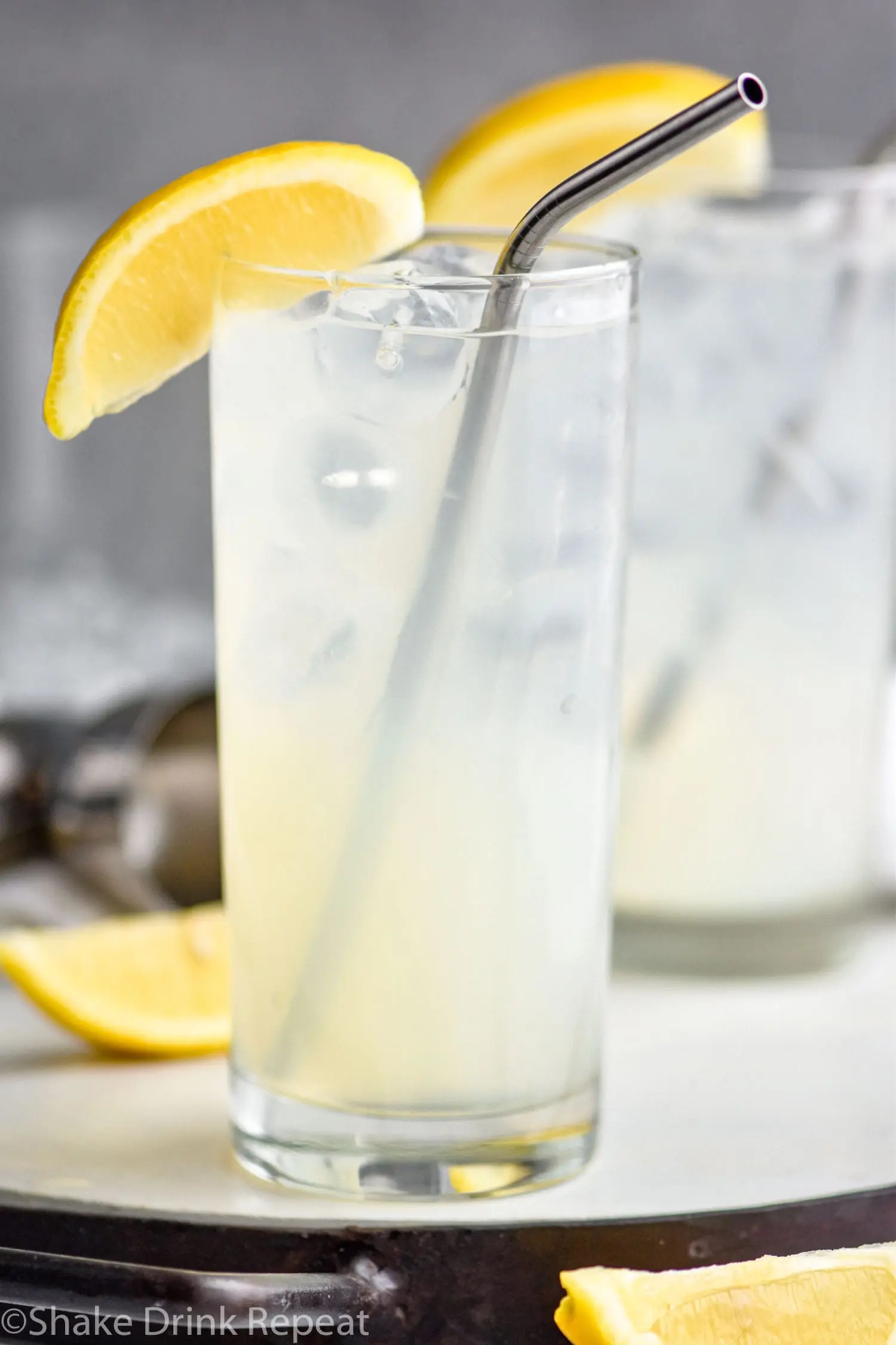 two glasses of rum collins with ice, lemon and straws