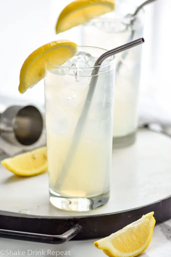 two glasses of rum collins with ice, lemon, and straws