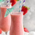 two glasses of frozen strawberry Colada drink with straws and umbrella