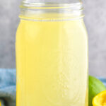 jar of homemade sweet and sour mix with lemons and limes