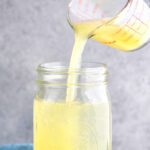 Jar of homemade sweet and sour mix with lemons and limes