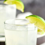 glass of vodka gimlet cocktail recipe with ice and limes