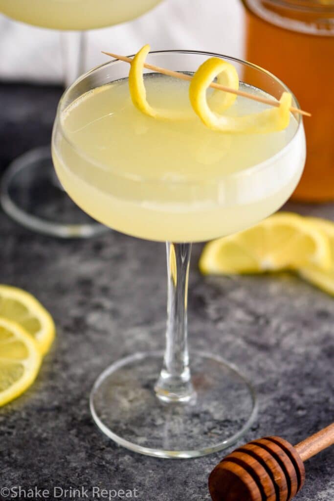 glass of bees knees cocktail with lemon and honey syrup