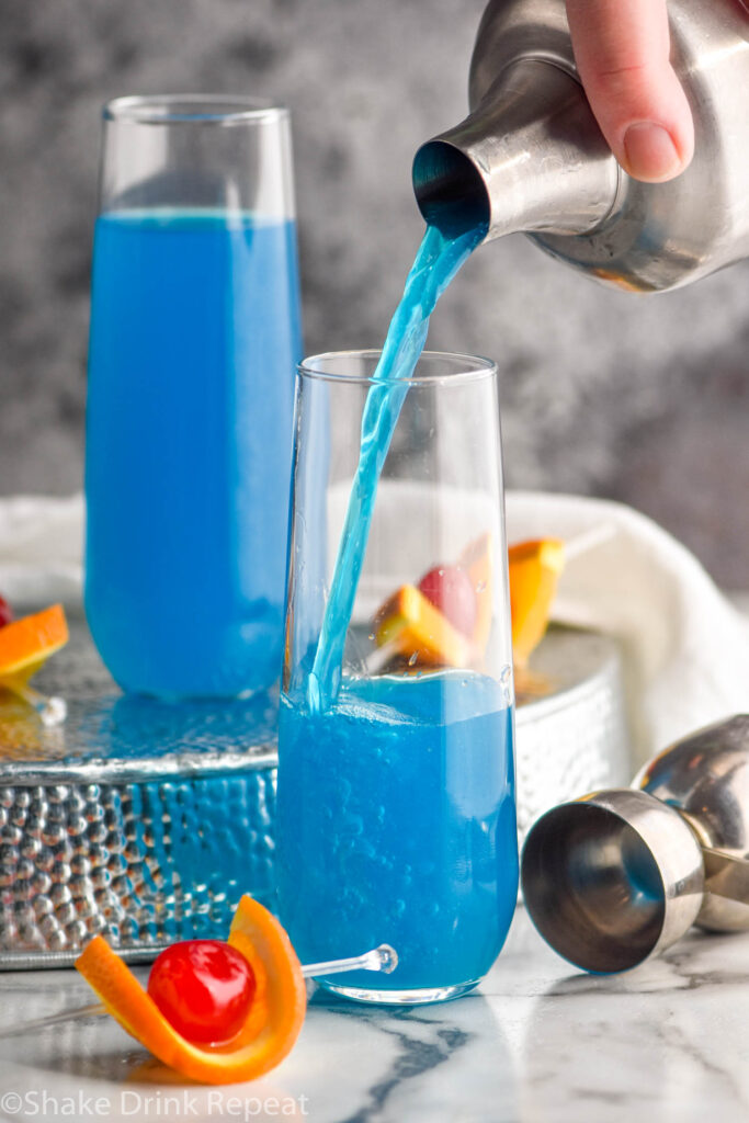 two glasses of blue kamikaze recipe with orange and cherry garnish