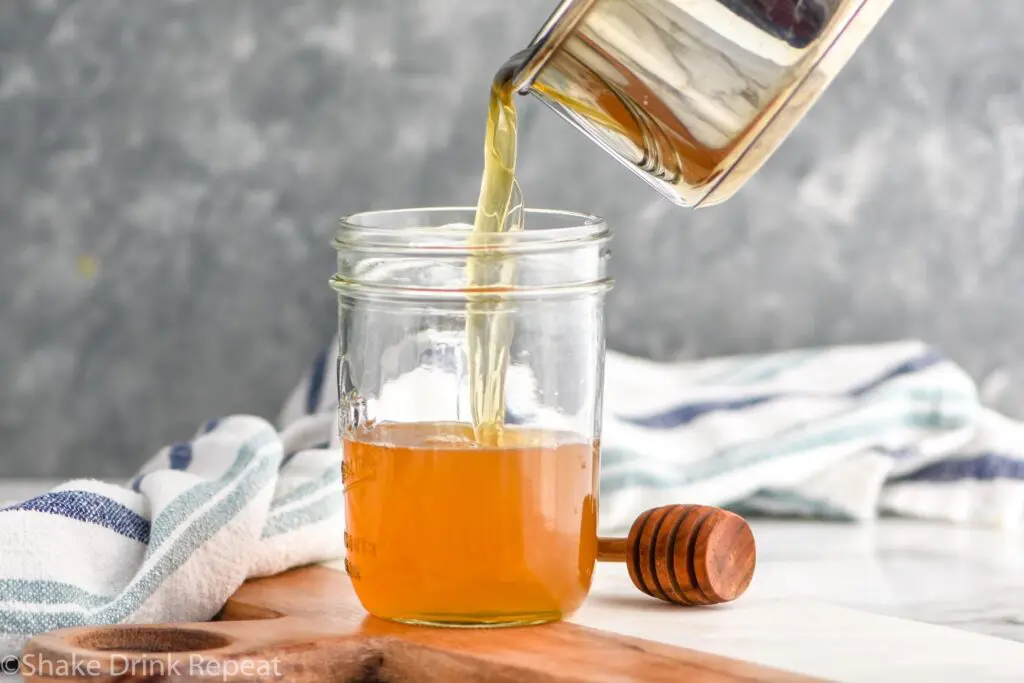 making homemade honey syrup recipe and pouring into jar