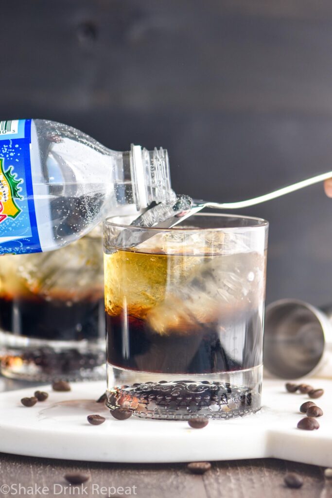 glass of mind eraser cocktail ingredients with ice, club soda water, and coffee beans