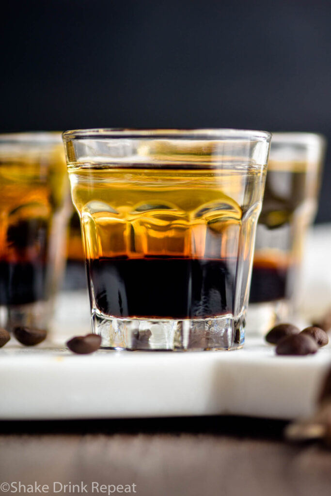 glass of layered mind eraser shot surrounded by coffee beans