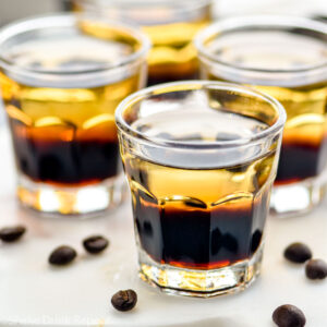 glasses of layered mind eraser shots surrounded by coffee beans