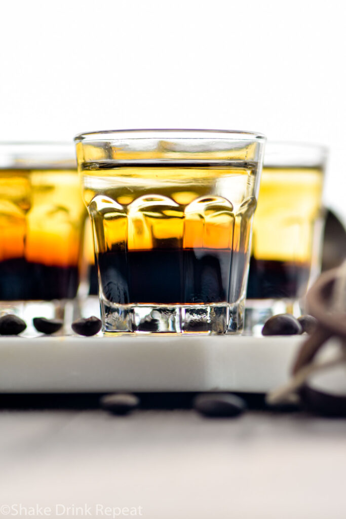 glasses of layered mind eraser shots surrounded by coffee beans