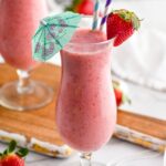 two glasses of strawberry colada cocktail with straws and umbrella