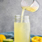 jar of homemade sweet and sour mix with lemons and limes