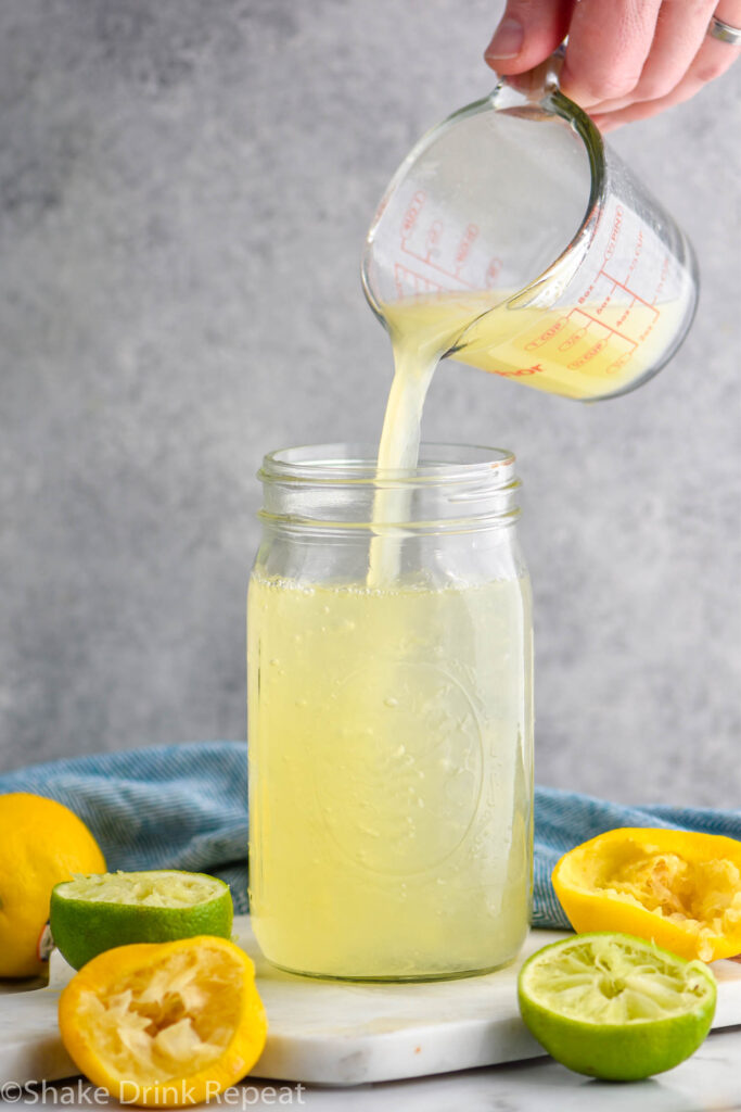jar of homemade sweet and sour mix with lemons and limes