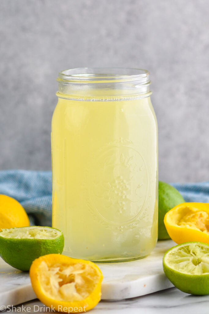 jar of homemade sweet and sour mix with lemons and limes