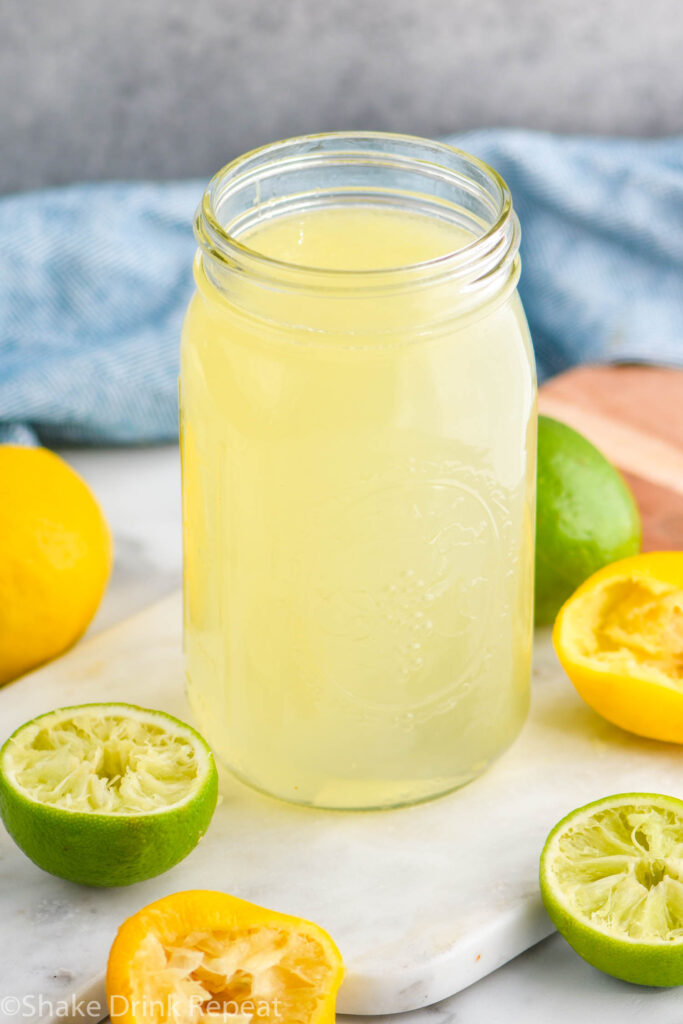 jar of homemade sweet and sour mix with lemons and limes