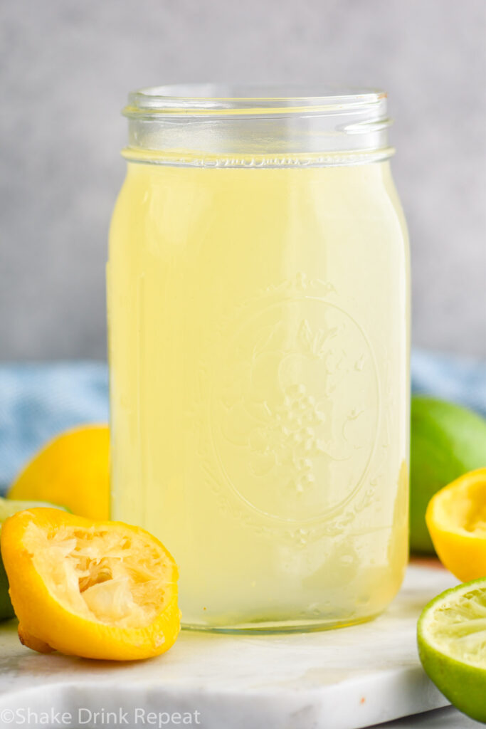 jar of homemade sweet and sour mix with lemons and limes