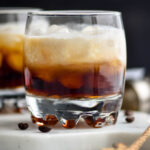 Glass of white russian cocktail with ice and coffee beans